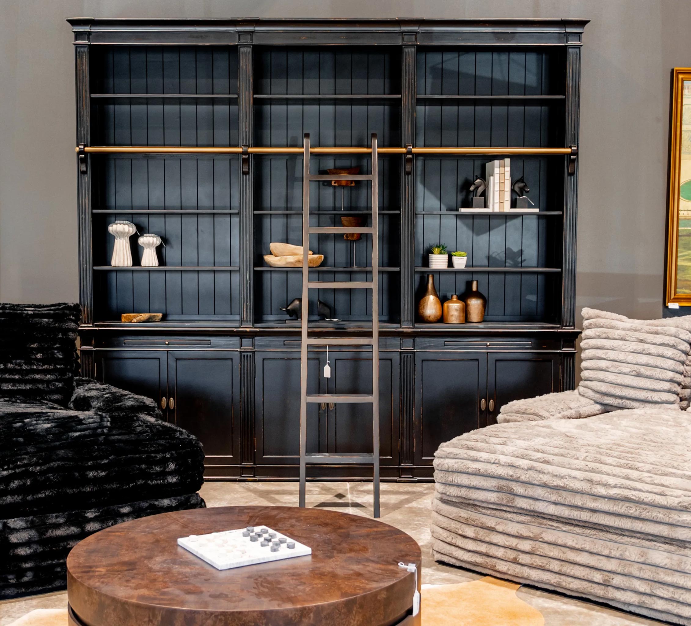 Large dark wooden bookshelf with shelves and a ladder in a living room setting.